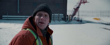 Movie still from “The Ice Road” (2021), directed by Jonathan Hensleigh – A man wearing a winter coat and a hat standing in the snow; Close Up shot, Over the shoulder angle