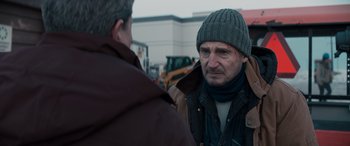 Movie still from “The Ice Road” (2021), directed by Jonathan Hensleigh – A man wearing a hat talking to another man outside; Close Up shot, Over the shoulder angle