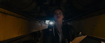 Movie still from “The Ice Road” (2021), directed by Jonathan Hensleigh – A woman is holding a flashlight in a dark room; Medium shot, Low angle