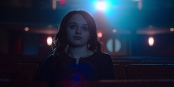 Movie still from “The In Between” (2022), directed by Arie Posin – A woman sitting in front of a microphone in a dark room; Close Up shot, Low angle