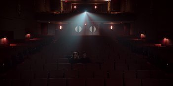 Movie still from “The In Between” (2022), directed by Arie Posin – Two people are sitting in a dark theater; Extreme Wide shot, High angle