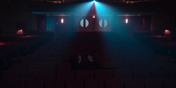 Movie still from “The In Between” (2022), directed by Arie Posin – Two people are sitting in a dark auditorium; Extreme Wide shot, High angle