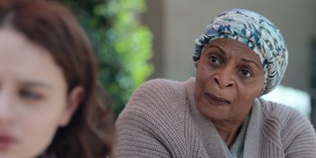 Movie still from “The In Between” (2022), directed by Arie Posin – An older woman wearing a head scarf and a sweater; Close Up shot, Over the shoulder angle