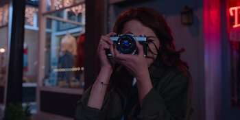 Movie still from “The In Between” (2022), directed by Arie Posin – A woman taking a picture with a camera; Close Up shot, Over the shoulder angle
