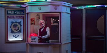 Movie still from “The In Between” (2022), directed by Arie Posin – An older man standing in a booth at a restaurant; Wide shot, High angle