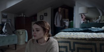 Movie still from “The In Between” (2022), directed by Arie Posin – A woman sitting on a bed in a room with another woman standing in the background; Medium shot, Over the shoulder angle