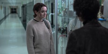 Movie still from “The In Between” (2022), directed by Arie Posin – A woman standing in front of a glass case; Medium shot, Over the shoulder angle