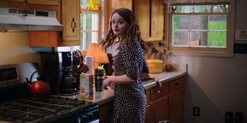 Movie still from “The In Between” (2022), directed by Arie Posin – A woman standing in a kitchen next to a counter; Medium shot, Over the shoulder angle