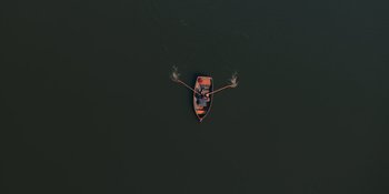 Movie still from “The In Between” (2022), directed by Arie Posin – An aerial view of a person rowing a boat in the water; Extreme Wide shot, Overhead angle