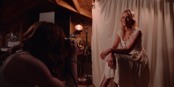 Movie still from “The In Between” (2022), directed by Arie Posin – A woman sitting on a chair in front of a woman taking a picture; Medium shot, Low angle