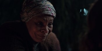 Movie still from “The In Between” (2022), directed by Arie Posin – An older woman wearing a headscarf looking at the camera; Close Up shot, Over the shoulder angle