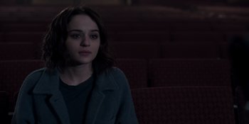 Movie still from “The In Between” (2022), directed by Arie Posin – A woman sitting in front of a row of seats; Medium shot, Over the shoulder angle