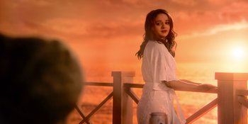 Movie still from “The In Between” (2022), directed by Arie Posin – A woman in a white robe standing next to a railing at sunset; Medium shot, Over the shoulder angle