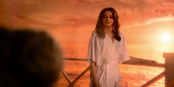 Movie still from “The In Between” (2022), directed by Arie Posin – A woman in a white dress standing in front of a sunset; Medium shot, Over the shoulder angle