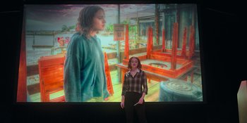 Movie still from “The In Between” (2022), directed by Arie Posin – A woman standing in front of a large painting; Wide shot, Low angle