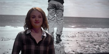 Movie still from “The In Between” (2022), directed by Arie Posin – A woman standing in front of an image of a man standing on a tree stump; Medium shot, Over the shoulder angle