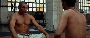 Movie still from “The Incredible Hulk” (2008), directed by Louis Leterrier – A man sitting on the ground in front of another man; Medium shot, Over the shoulder angle