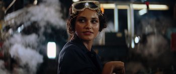 Movie still from “The Incredible Hulk” (2008), directed by Louis Leterrier – A woman wearing goggles while standing next to a building; Close Up shot, Over the shoulder angle