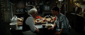 Movie still from “The Incredible Hulk” (2008), directed by Louis Leterrier – Two men sitting at a table in front of plates of hot dogs; Medium shot, Over the shoulder angle