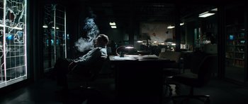 Movie still from “The Incredible Hulk” (2008), directed by Louis Leterrier – A man sitting at a desk in a dark room; Wide shot, Low angle