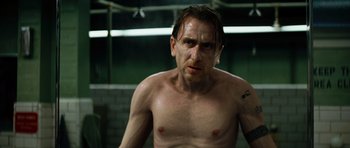 Movie still from “The Incredible Hulk” (2008), directed by Louis Leterrier – A man with a tattoo on his arm is looking at the camera; Close Up shot, Low angle