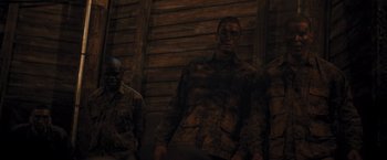 Movie still from “The Inspection” (2022), directed by Elegance Bratton – A group of men standing next to each other in front of a wooden wall; Medium shot, Low angle