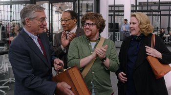 Movie still from “The Intern” (2015), directed by Nancy Meyers – A group of people that are standing up; Medium shot, Over the shoulder angle