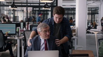 Movie still from “The Intern” (2015), directed by Nancy Meyers – An older man sitting in front of a computer with a younger man standing next to him; Medium shot, Over the shoulder angle