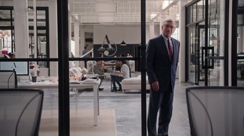 Movie still from “The Intern” (2015), directed by Nancy Meyers – A man in a suit and tie standing in an office; Wide shot, Over the shoulder angle