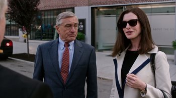 Movie still from “The Intern” (2015), directed by Nancy Meyers – An older man and a younger woman standing next to each other on the sidewalk; Medium shot, Over the shoulder angle