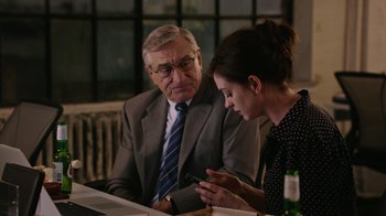 Movie still from “The Intern” (2015), directed by Nancy Meyers – An older man and a younger woman are looking at a piece of paper; Medium shot, Over the shoulder angle