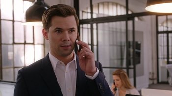 Movie still from “The Intern” (2015), directed by Nancy Meyers – A man talking on a cell phone while standing in front of a woman; Close Up shot, Over the shoulder angle