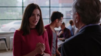 Movie still from “The Intern” (2015), directed by Nancy Meyers – A woman in a red dress talking to a man in glasses; Medium shot, Over the shoulder angle