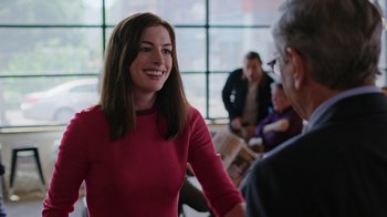 Movie still from “The Intern” (2015), directed by Nancy Meyers – A woman in a red shirt is talking to a man; Medium shot, Over the shoulder angle