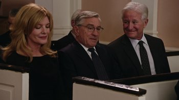 Movie still from “The Intern” (2015), directed by Nancy Meyers – A man and two women in a suit and tie; Medium shot, Over the shoulder angle
