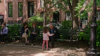 Movie still from “The Intern” (2015), directed by Nancy Meyers – A little girl sitting on a park bench with an older man and woman; Wide shot, Over the shoulder angle
