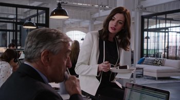 Movie still from “The Intern” (2015), directed by Nancy Meyers – A man and a woman are sitting at a table; Medium shot, Over the shoulder angle