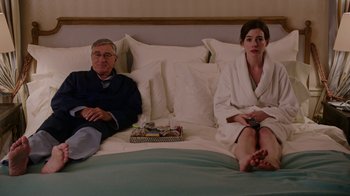 Movie still from “The Intern” (2015), directed by Nancy Meyers – A man and a woman sitting on top of a bed; Medium shot, Over the shoulder angle