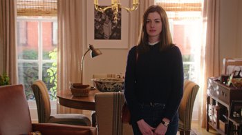 Movie still from “The Intern” (2015), directed by Nancy Meyers – A woman standing in front of a table in a living room; Medium shot, Over the shoulder angle