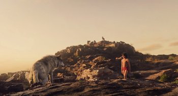 Movie still from “The Jungle Book” (2016), directed by Jon Favreau – A person and a wolf on a rocky hill; Wide shot, Low angle