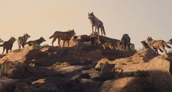 Movie still from “The Jungle Book” (2016), directed by Jon Favreau – A group of wild animals standing on top of a rock formation; Extreme Wide shot, Low angle