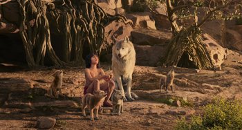Movie still from “The Jungle Book” (2016), directed by Jon Favreau – A woman sitting on the ground next to a wolf; Wide shot, High angle