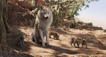Movie still from “The Jungle Book” (2016), directed by Jon Favreau – A wolf sitting on the ground next to a group of small animals; Wide shot, Low angle