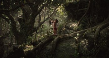 Movie still from “The Jungle Book” (2016), directed by Jon Favreau – A woman standing on a rock in the woods; Extreme Wide shot, Low angle