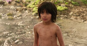 Movie still from “The Jungle Book” (2016), directed by Jon Favreau – A young boy standing next to a river; Close Up shot, High angle