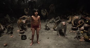 Movie still from “The Jungle Book” (2016), directed by Jon Favreau – A boy standing in front of a group of monkeys; Wide shot, High angle