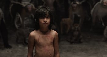 Movie still from “The Jungle Book” (2016), directed by Jon Favreau – A young boy is standing in front of a group of monkeys; Medium shot, Low angle
