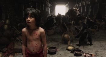 Movie still from “The Jungle Book” (2016), directed by Jon Favreau – A young boy standing in a room full of animals; Medium shot, High angle