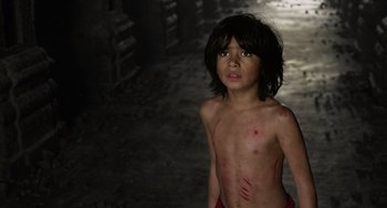 Movie still from “The Jungle Book” (2016), directed by Jon Favreau – A young boy with red marks on his body; Medium shot, High angle
