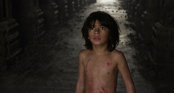 Movie still from “The Jungle Book” (2016), directed by Jon Favreau – A young boy with red marks on his face and chest; Medium shot, High angle